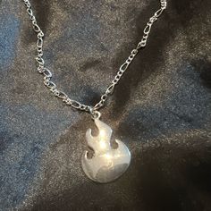 a silver necklace with a star wars symbol on the front and back of it, sitting on a black fabric