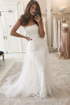 a woman in a wedding dress looking at her cell phone and taking a selfie