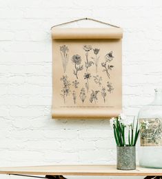 a wooden table topped with a vase filled with flowers next to a painting on the wall