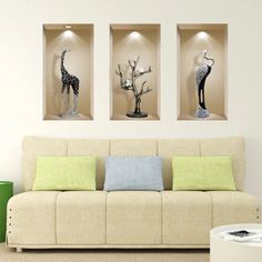 three giraffes are displayed on the wall above a couch in a living room