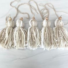 four tasselled ornaments hanging on a white marble counter with the word love spelled in gold