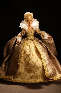 the doll is wearing a gold dress with white ruffles and a tiara