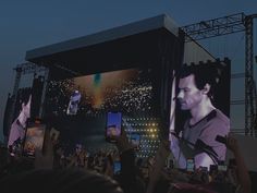 a large screen with a man on it and people holding up cell phones in front of him