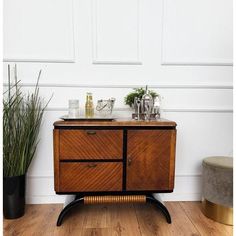 a wooden cabinet sitting on top of a hard wood floor next to a potted plant