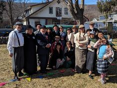 a group of people standing next to each other in front of a tree and house