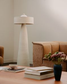 a living room with two couches, a table and a lamp in the corner