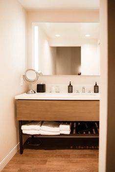 a bathroom with a sink, mirror and towels on the shelf in front of it