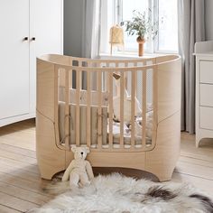 a baby crib with a teddy bear next to it in a room filled with white furniture