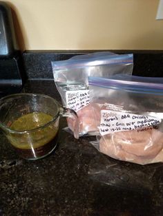 two bags of food sitting on top of a counter next to a glass bowl filled with green liquid