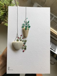 two small rocks with plants on them hanging from necklaces