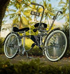 a motorcycle parked on the side of a road next to some bushes and trees in front of palm trees