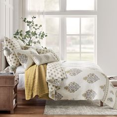 a bed with white sheets and pillows in front of a window next to a dresser