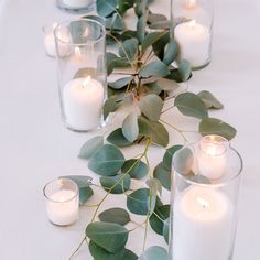 the table is set with candles and eucalyptus leaves