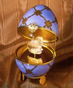 an egg with a ring in it sitting on top of a glass container and gold trimming