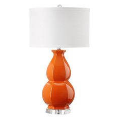 an orange table lamp with a white shade on the top and bottom part of it