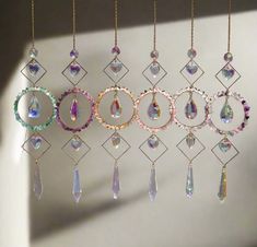 a group of different colored glass beads hanging from a chain on a white wall next to a window