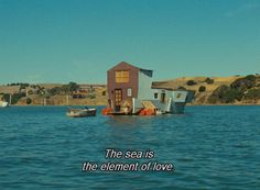 a house floating on top of a lake next to a boat with the words the sea is the element of love