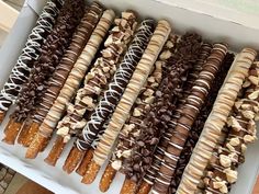 a box filled with lots of different types of donuts and pretzel sticks