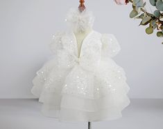 Let your little one shine in our Sequin Ribbon Baby Girl Wedding Dress, perfect for making a statement at any special occasion. This elegant birthday pearl stone tutu dress features a stunning sequin ribbon design, adding sparkle and glamour to your baby's outfit. The princess-style puffy dress, with layers of soft tulle, creates a dreamy, elegant look, making it ideal for weddings, birthdays, or any formal event. Whether it's for a birthday celebration or as a wedding guest, this tulle dress en White Princess Dress For Easter, White Tulle Easter Dress, White Dress For Easter Dress-up, White Tutu Dress For Easter, White Tulle Tutu Dress For Easter, Easter White Princess Dress, White Dress For Easter Birthday, White Princess Dress For Easter Party, White Tutu Dress For Easter Party