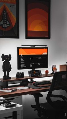 a desk with a computer monitor, keyboard and mouse on it in front of two framed pictures