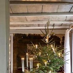 a small christmas tree is in the middle of a dining room table with candles on it