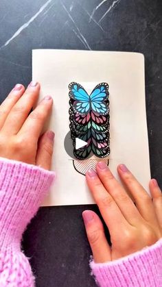 a person holding up a card with a butterfly on it and another hand next to it