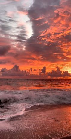 the sun is setting at the beach with waves crashing in front of it and clouds