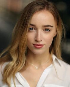 a close up of a person wearing a white shirt and blonde hair with blue eyes