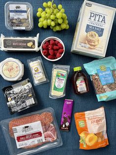 an assortment of food items laid out on a blue surface with grapes, nuts, and other foodstuffs