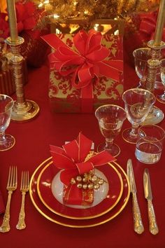 the table is set with silverware and red napkins, wrapped in gold foil