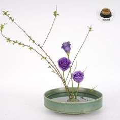 three purple flowers are in a green vase