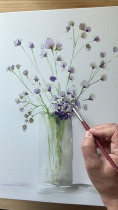 a person is painting flowers in a vase with watercolor pencils on the table