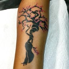 a woman with a tree tattoo on her arm is holding onto the branch of a blossoming tree