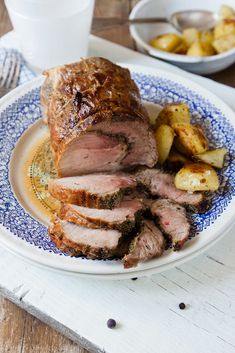 a plate that has some meat on it and potatoes in the bowl next to it