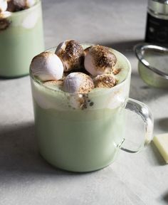 two mugs filled with hot chocolate and marshmallows on top of a table