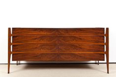 a wooden dresser sitting on top of a carpeted floor next to a white wall