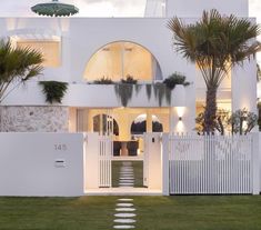 a white house with palm trees in the front yard and stairs leading up to it