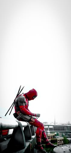 a man in red is sitting on top of a building with his legs crossed out