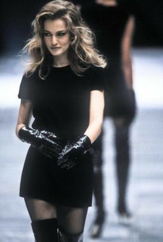 a woman walking down a runway wearing black gloves