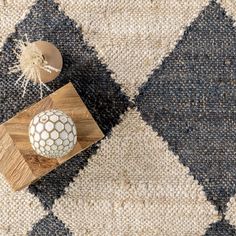 a white ball sitting on top of a wooden block in front of a black and white checkered rug