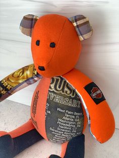 an orange teddy bear sitting on top of a white counter next to a bottle of beer