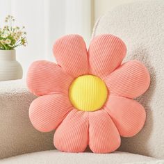 a pink flower pillow sitting on top of a white chair