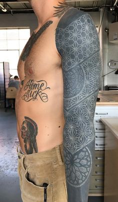 a man with tattoos on his arm standing in a kitchen