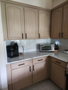 a kitchen with wooden cabinets and white counter tops, including a coffee maker on the corner