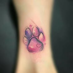 a small paw print on the side of a woman's leg with pink and purple ink