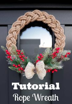 a rope wreath with red berries and pine cones hanging on the front door for christmas