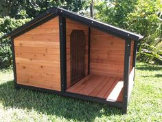 a dog house made out of wood and black trim on the outside, with its door open