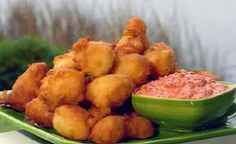 a green plate topped with tater tots next to a bowl of red sauce