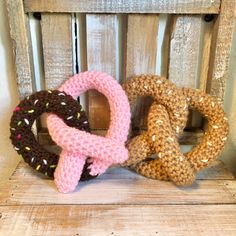 three knitted pretzels sitting on top of a wooden bench next to each other