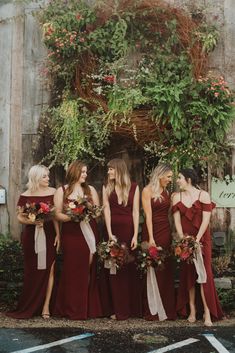 a group of women standing next to each other in front of a wooden building with ivy growing on it